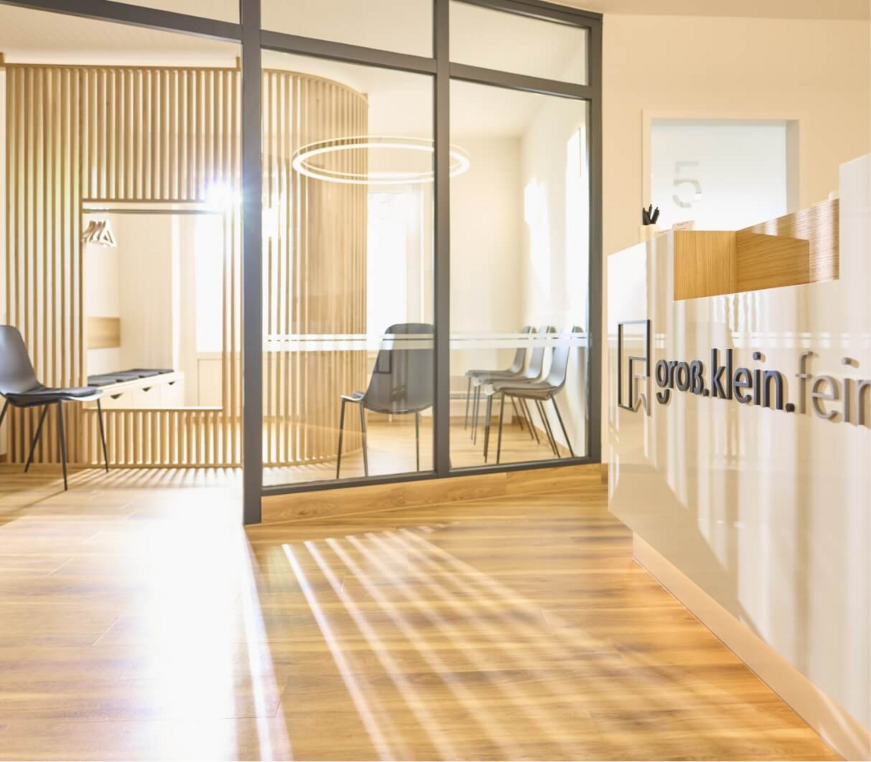 Der lichtdruchflutete Eingangsbereich der Zahnarztpraxis groß.klein.fein. in Fürth ist mit hellem Holz gestaltet